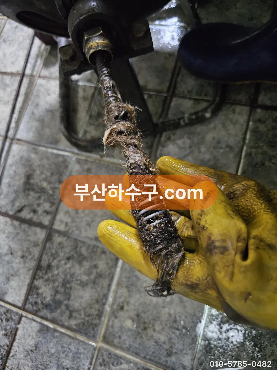 스프링 장비 끝에 걸려 나온 굳은 슬러지와 이물 덩어리, 물살로는 안 떨어지는 층